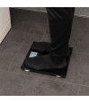 Personne debout se pesant dans la salle de bain avec le Pèse-personne parlant noir