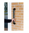 Main saisissant la barre d'appui extérieure PRIMA 46 cm noire fixée sur façade en brique près d'une porte d'entrée