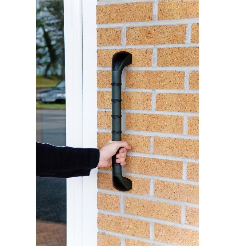 Main saisissant la barre d'appui extérieure PRIMA 46 cm noire fixée sur façade en brique près d'une porte d'entrée