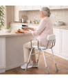 Personne senior préparant le repas, confortablement assise sur le tabouret assis-debout ergonomique Kizine, dans sa cuisine.
