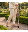 Femme marchande avec une canne fleurie dans un jardin, symbole de mobilité élégante et colorée.