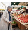 Femme utilisant une canne de marche à motif fraise dans un marché traditionnel en France.