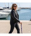Femme moderne en veste en cuir au port avec sa canne de marche originale et féminine.