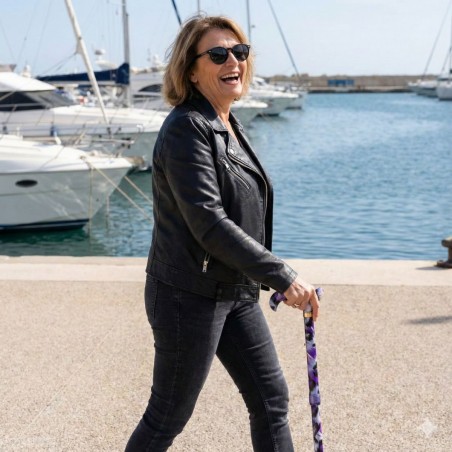 Femme moderne en veste en cuir au port avec sa canne de marche originale et féminine.