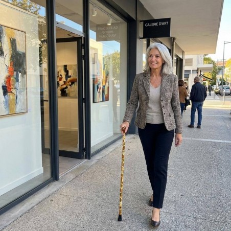 Femme 50 ans chic présentant sa canne de marche motif tournesols, pièce d'art subtile et très élégante.