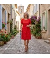 Femme senior en robe de lin rouge marchant dans une rue provençale avec une canne de marche Bleuets des Champs