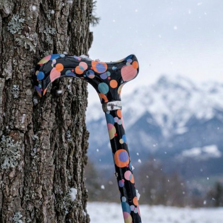 Jolie canne de marche fantaisie, appuyée contre un arbre, sous une douce chute de neige.
