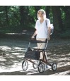 Senior actif marchant en forêt avec son rollator tout-terrain à 4 roues, robuste et doté d'une structure rigide.