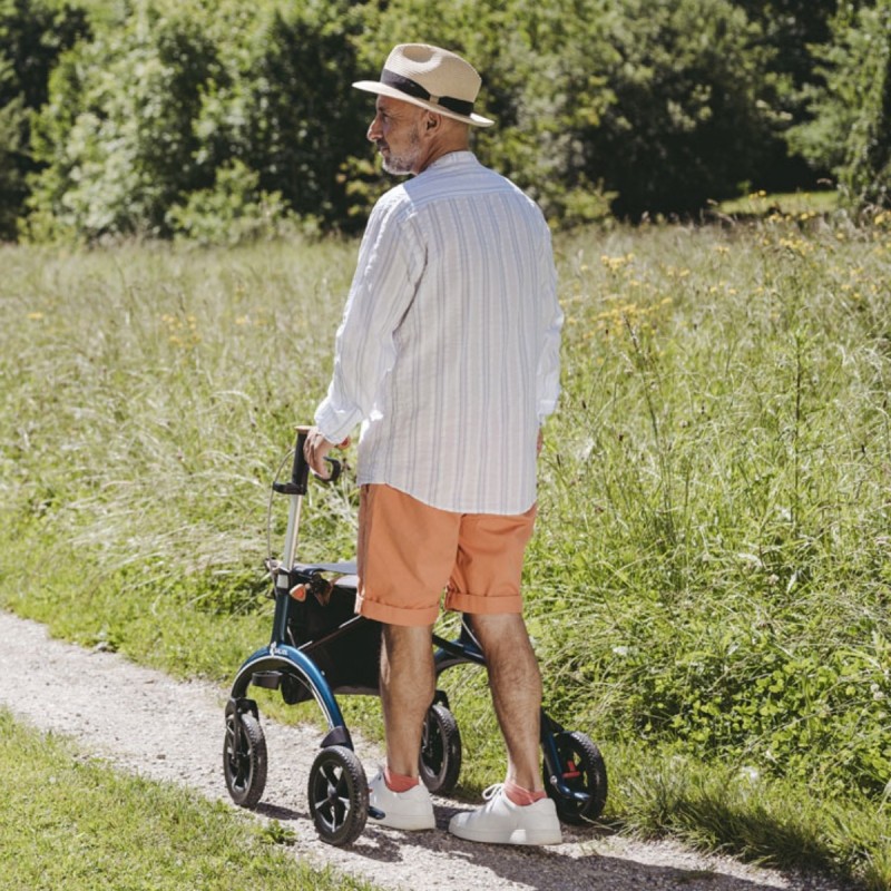 Senior dans un jardin de terre, prouvant que ce rollator en carbone est robuste et stable.