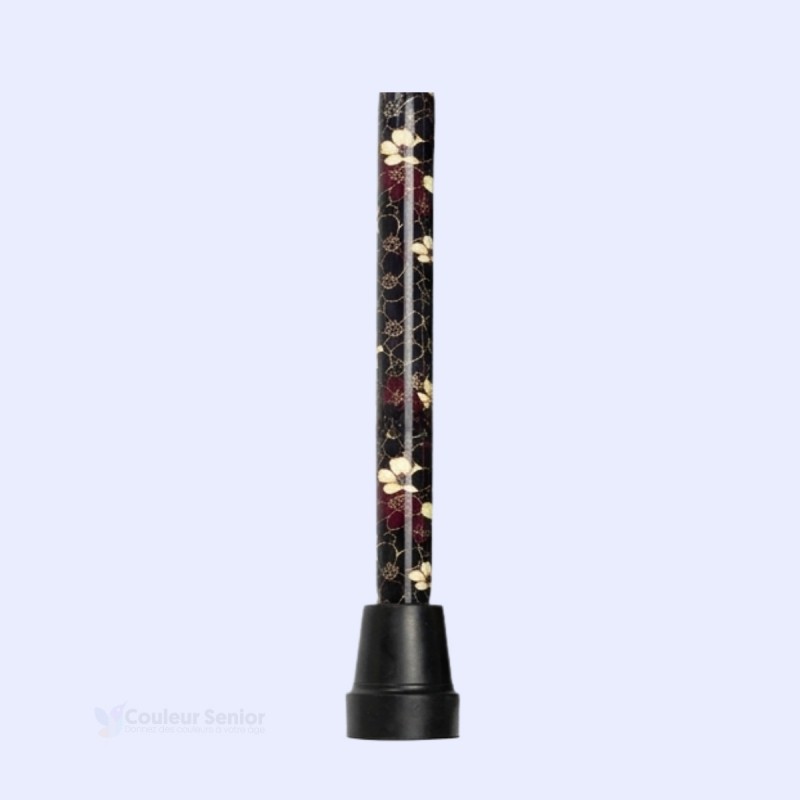 Focus sur l'embout de la canne de marche noire, orné de fleurs, discret et sobre, pour femme.