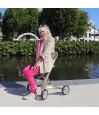 Femme assise et souriante avec déambulateur 4 roues Carbon Ultralight ACRE or champagne