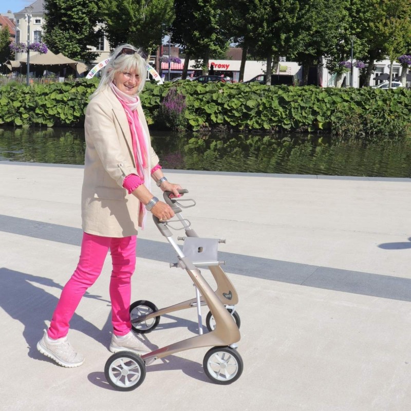 Femme senior marchant avec déambulateur 4 roues Carbon Ultralight ACRE or champagne