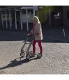 Femme senior marchant sur des pavés avec un déambulateur 4 roues Carbon Ultralight ACRE or champagne