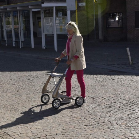 Femme senior marchant sur des pavés avec un déambulateur 4 roues Carbon Ultralight ACRE or champagne