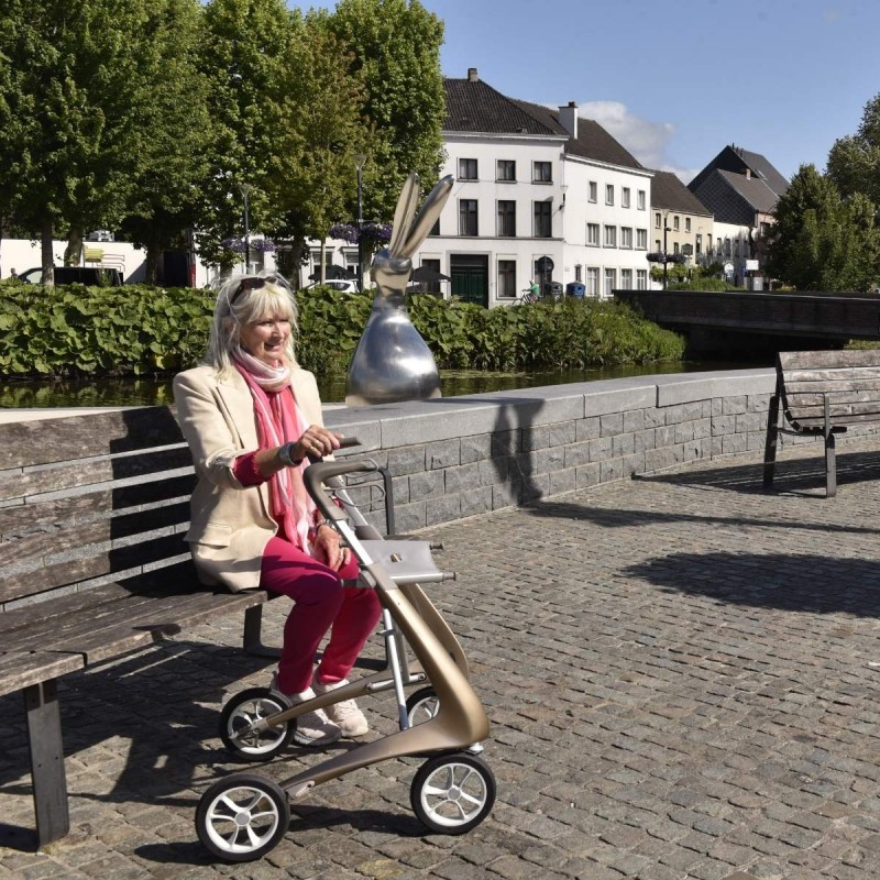Femme senior sur un banc avec son déambulateur 4 roues Carbon Ultralight ACRE or champagne à ses côtés