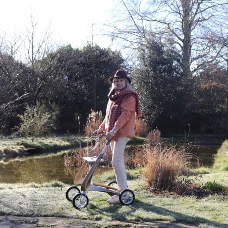 Femme âgée debout avec son déambulateur 4 roues Carbon Ultralight ACRE or champagne