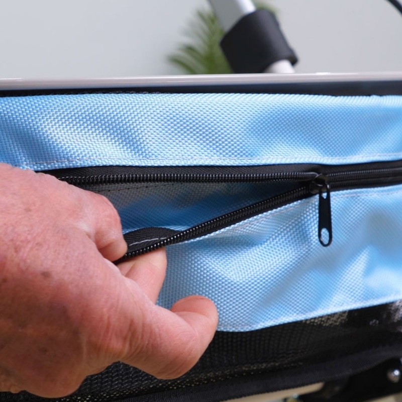 Senior ouvrant la fermeture éclair du sac bleu amovible du déambulateur Neo Indoor. Pratique pour l’intérieur de l’appartement.