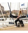 Femme assise sur le siège du rollator Rollz Flex noir au bord d'un port de plaisance