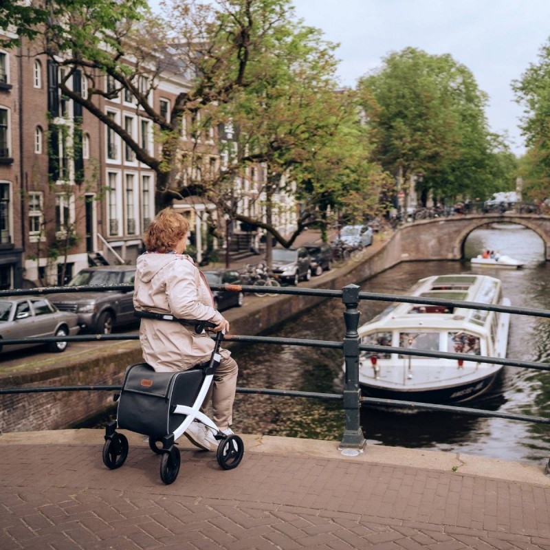 Dame senior assise sur rollator Rollz Flex blanc sur un pont face aux canaux d'Amsterdam