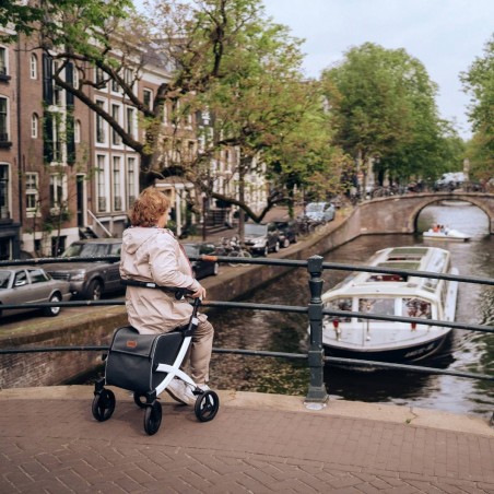 Dame senior assise sur rollator Rollz Flex blanc sur un pont face aux canaux d'Amsterdam
