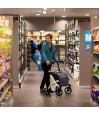Dame senior poussant le rollator caddy Rollz Flex blanc dans les rayons d'un supermarché
