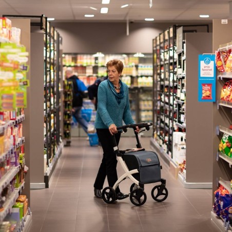 Dame senior poussant le rollator caddy Rollz Flex blanc dans les rayons d'un supermarché