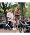Senior assise sur rollator Rollz Flex blanc discutant avec une jeune femme au bord d'un canal