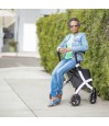 Dame élégante assise sur le siège du rollator Rollz Flex blanc en extérieur, détendue