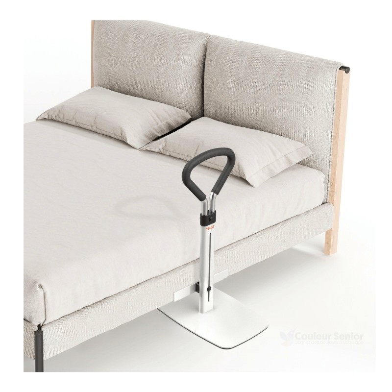 Poignee aide au lever Let's Get Up Trust installee avec socle blanc au bord d'un lit