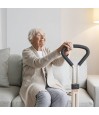 Senior souriante assise sur canape s'appuyant sur poignee Let's Get Up Trustcare blanche