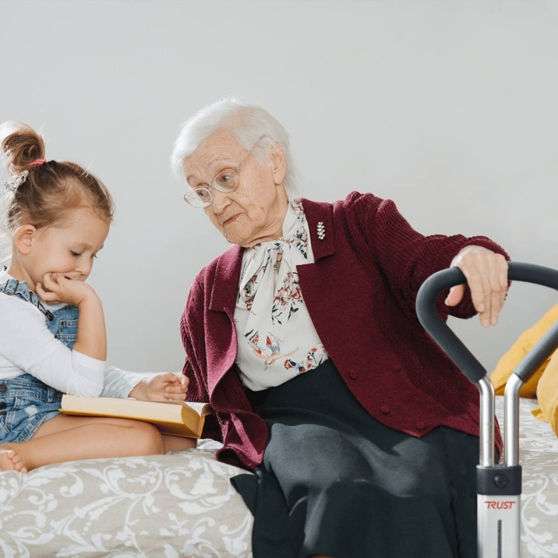 Grand-mere assise sur lit avec enfant tenant poignee aide au lever Let's Get Up Trust