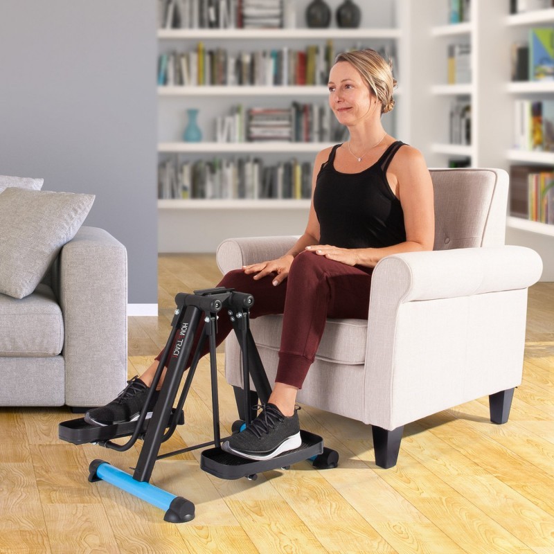 Femme senior utilisant le pédalier elliptique compact HomeTrack assise dans un fauteuil pour la rééducation des jambes