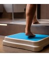 Personne utilisant un marchepied antidérapant bleu pour accéder à la douche en sécurité.