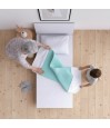 Grand-mère et enfant installant une alèse lavable turquoise sur un lit simple