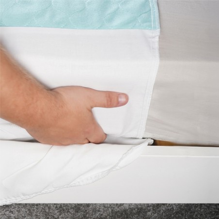 Gros plan installation du rabat de l'alèse lavable sous le matelas lit double – maintien sécurisé