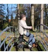Senior assis sur l'assise du déambulateur Let's Go Out vert Trustcare en pause jardin