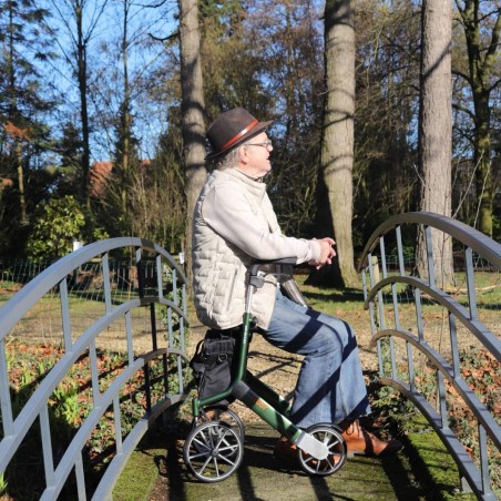 Senior assis sur l'assise du déambulateur Let's Go Out vert Trustcare en pause jardin