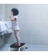 Enfant debout sur marchepied TrustCare Let's Step pour atteindre lavabo salle de bain