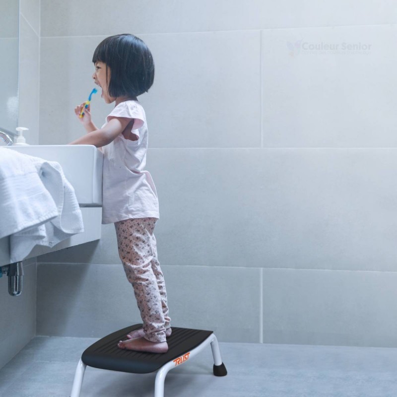 Enfant debout sur marchepied TrustCare Let's Step pour atteindre lavabo salle de bain