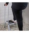 Personne debout sur marchepied sécurité blanc poignée appui salle de bain carrelage coloré