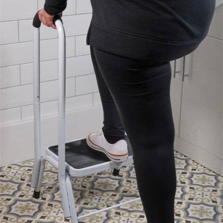 Personne debout sur marchepied sécurité blanc poignée appui salle de bain carrelage coloré