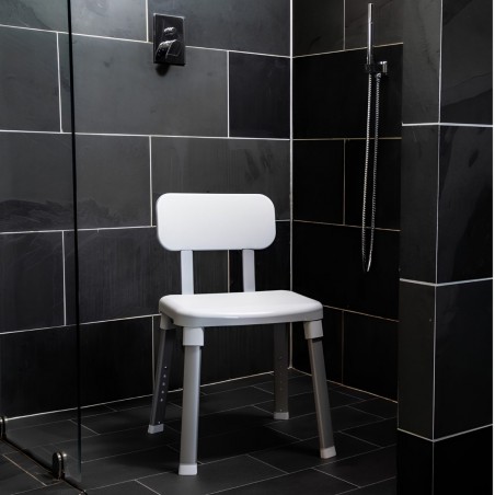 Élégante chaise de bain sans accoudoirs placée dans une cabine en ardoise noire moderne.