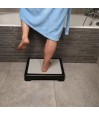 Personne en train de franchir le bord de la baignoire en s'aidant d'un marchepied de sécurité stable