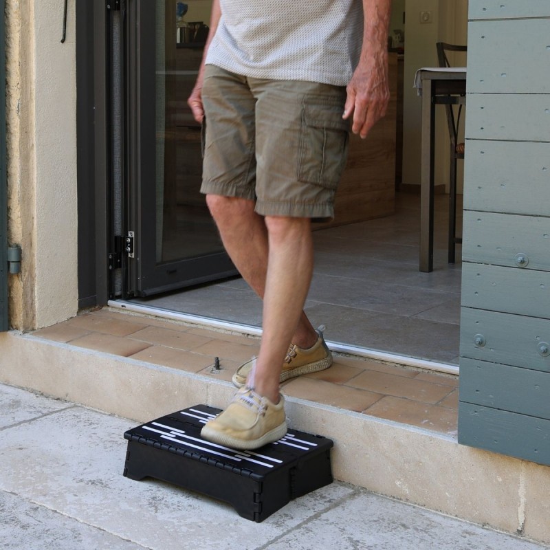 Senior sortant de la maison sans effort grâce au marchepied, protégeant efficacement les genoux.