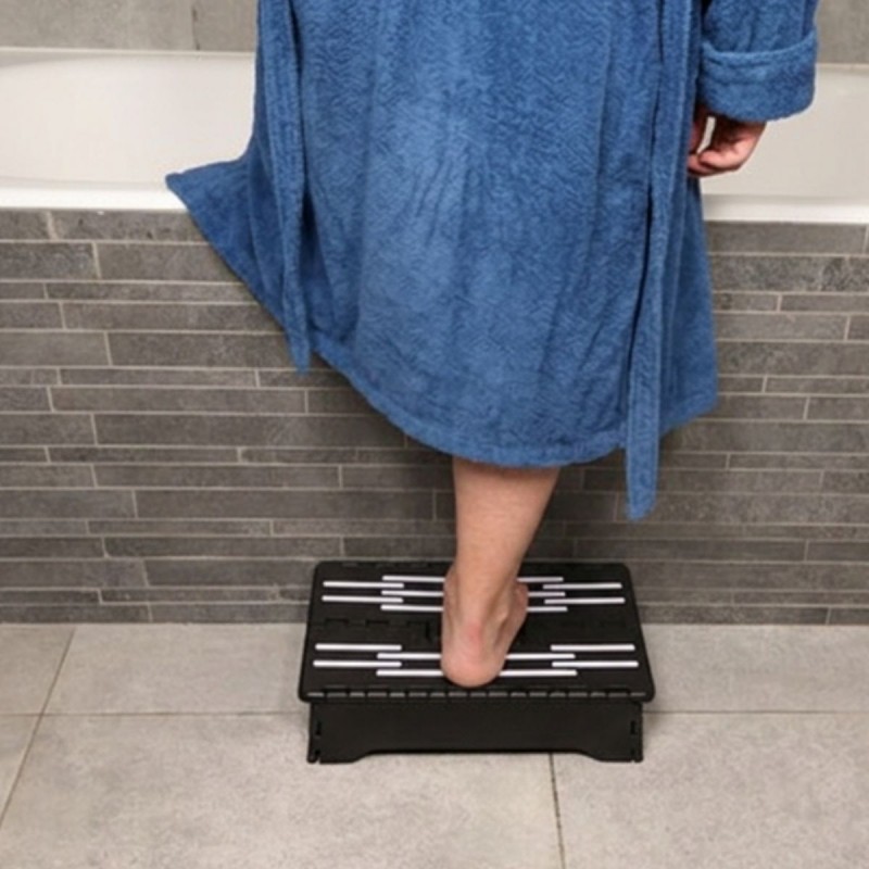 Senior entrant prudemment dans la baignoire grâce au marchepied, sécurité quotidienne assurée.