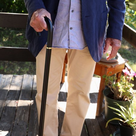 Homme senior marchant en ville. Sa canne classique noire offre prestance et un pas très sûr.
