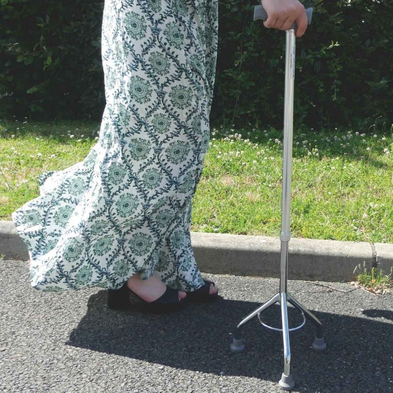 Femme utilisant la canne de marche tripode stable et sécurisante lors de ses déplacements quotidiens en extérieur